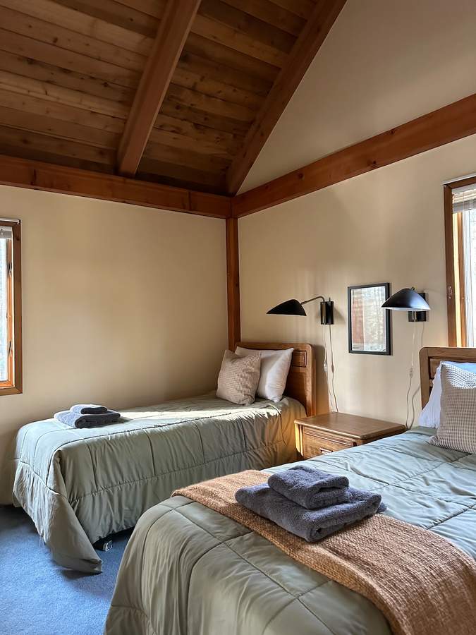 Upstairs bedroom three at Lofty Cabin with two twin beds beneath a vaulted wood ceiling